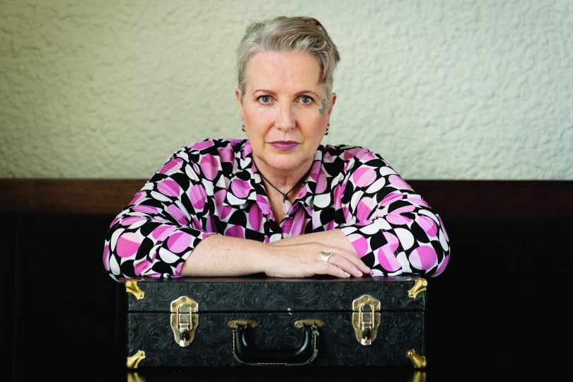 Dorothy-Jane Gosper with arms folded on suitcase.
