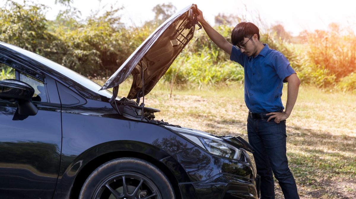 man looking at the engine of his car 