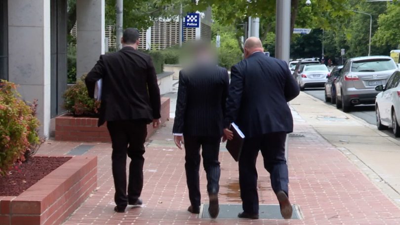 Criminal investigators from ACT Policing with one of the men arrested over alleged organised crime. 