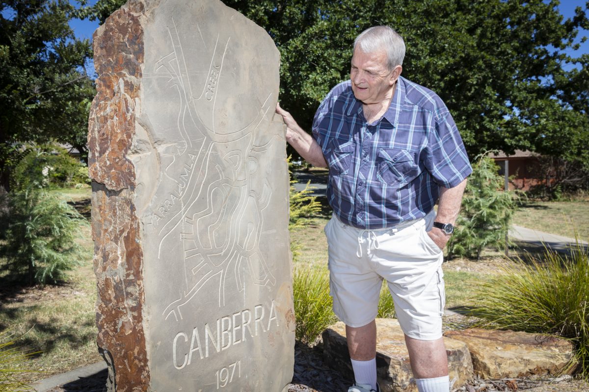 man standing next to a large stone memorial