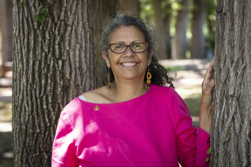 Woman smiling with hand on tree