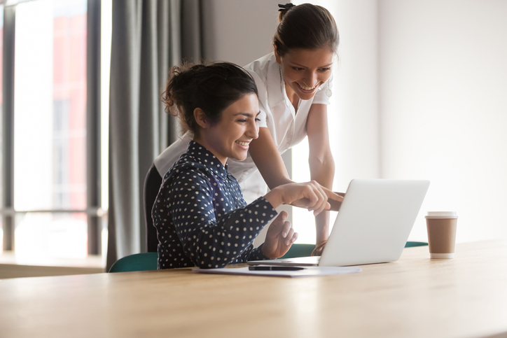 two people pointing to a laptop screen