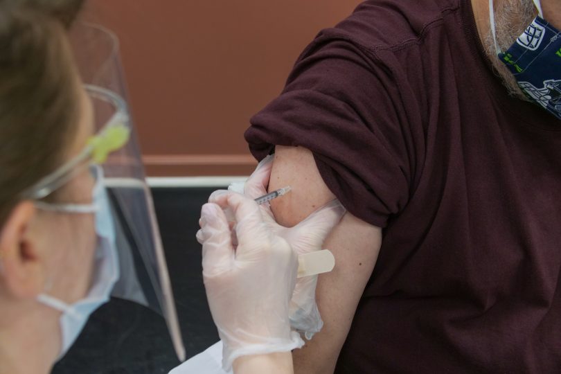 Nurse administering vaccination to man.