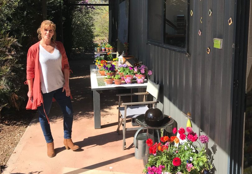 Alison Archbold outside her studio with flowers and painted pots.