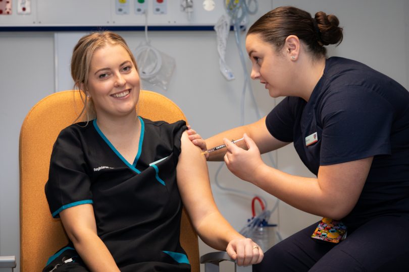 Nurse administering vaccine to another nurse