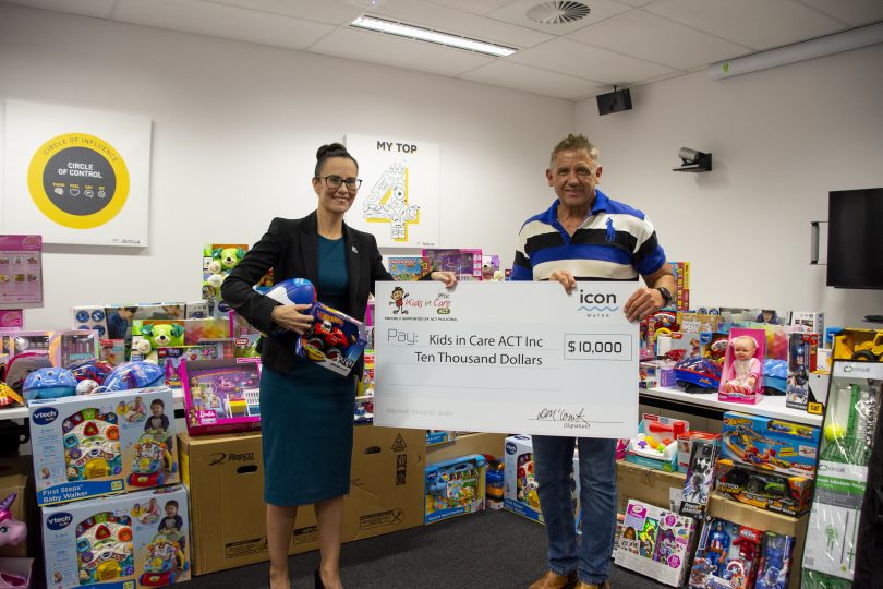 Woman and man surrounded by toys and holding a giant cheque