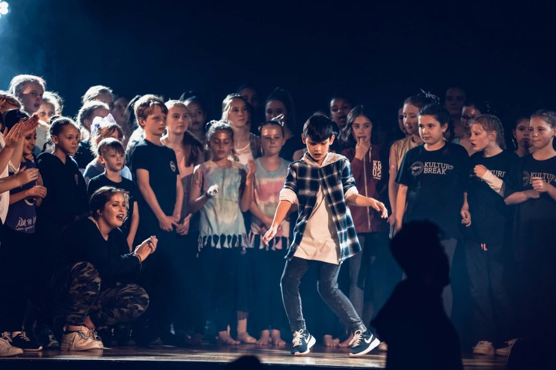 boy dancing on stage with crowd behind him