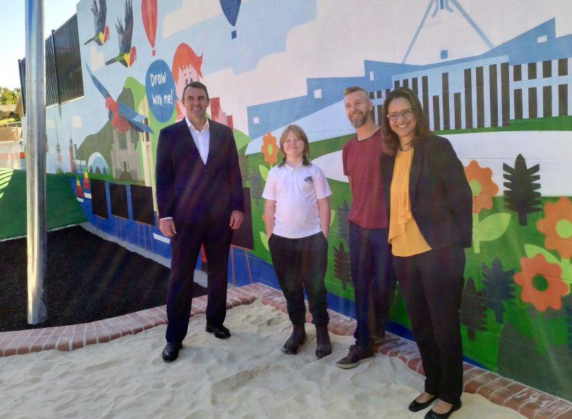 Joe Roff, Gus Filmer, Geoff Filmer and Enia Alberto standing front of the mural painted by Geoff