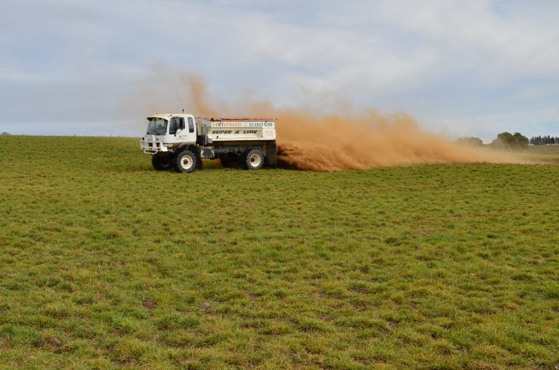 Truck spraying soil conditioner on rural property