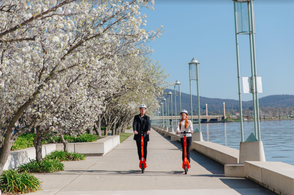 A woman and a man ride e-scooters