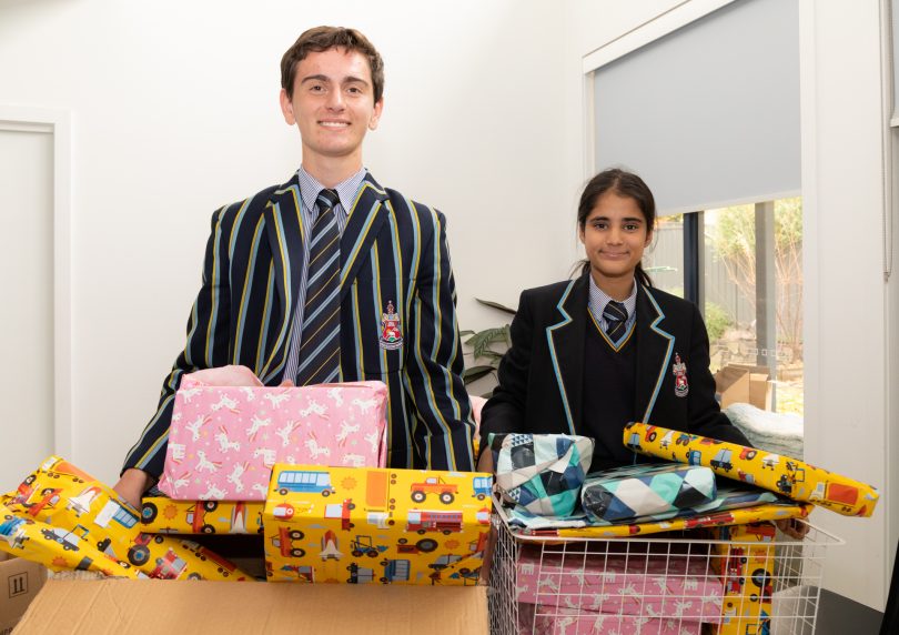 Two Canberra Grammar students holding boxes of gifts