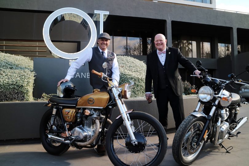 Simon Whittaker and John Aust standing with motorbikes outside QT Canberra hotel