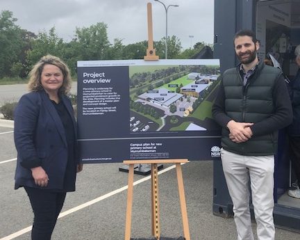 Wendy Tuckerman standing next to project-overview sign for Murrumbateman primary school