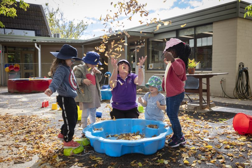 Barbara Butt playing with kids and leaves at Evatt Preschool