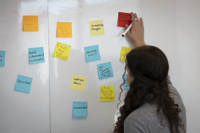 Woman sticking Post-it note on a wall