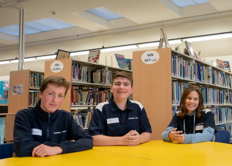 Three students sitting at a school desk