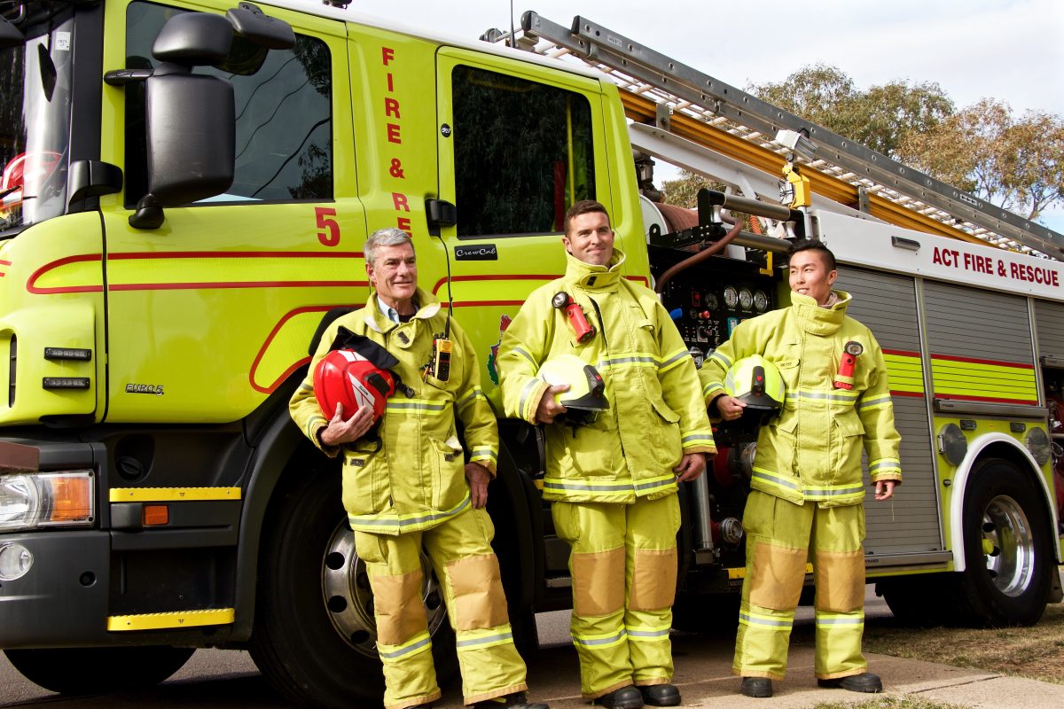 Three firefighters standing next to truck