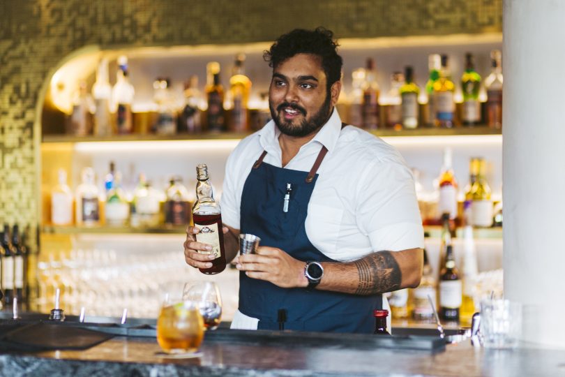 Geocon hospitality worker serving drink behind bar