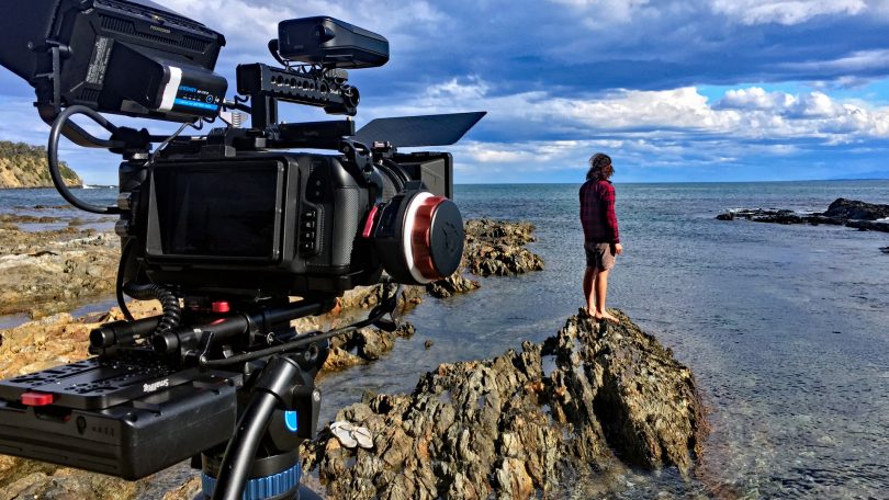 Camera filming man standing on coastal rocks