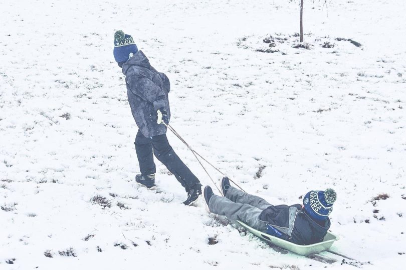 Two young boys go tobogganing at Crookwell