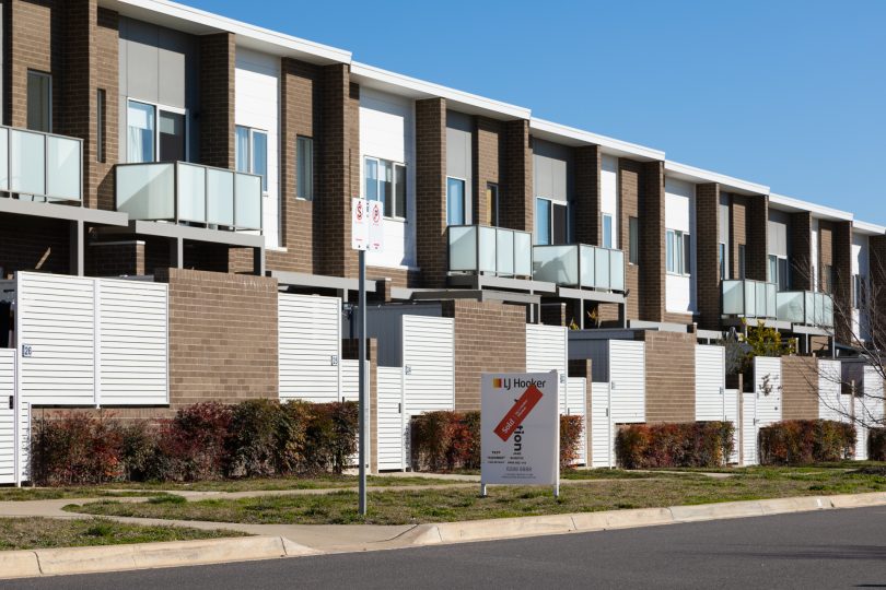 Sold sign in front of townhouse strip.