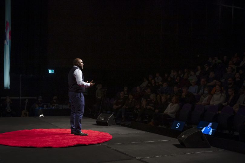 Alfred Chidembo speaking onstage at TEDxCanberra