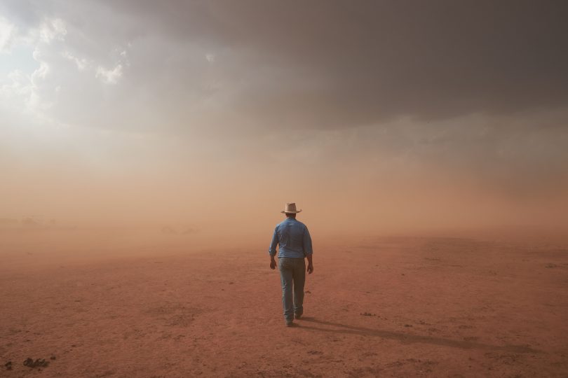 Farmer walking through dust storm