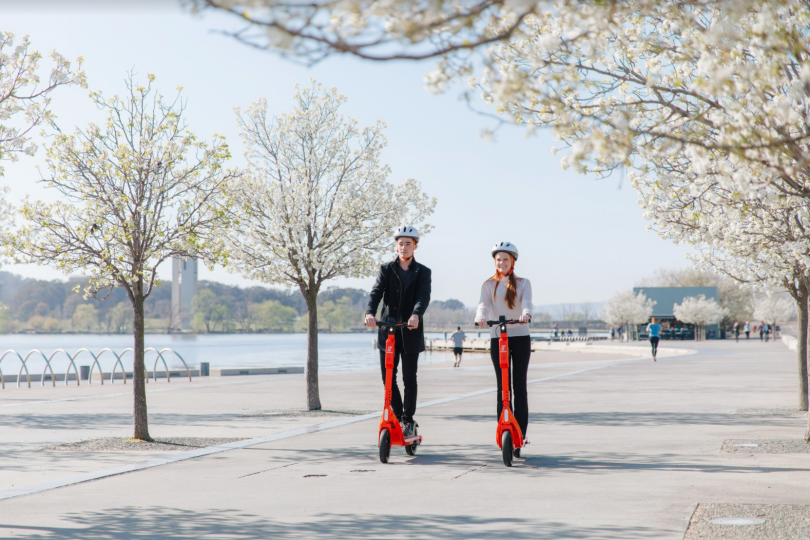 Man and woman riding Neuron Mobility e-scooters