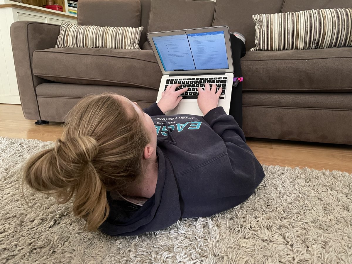 girl lying down with her laptop and legs on the couch