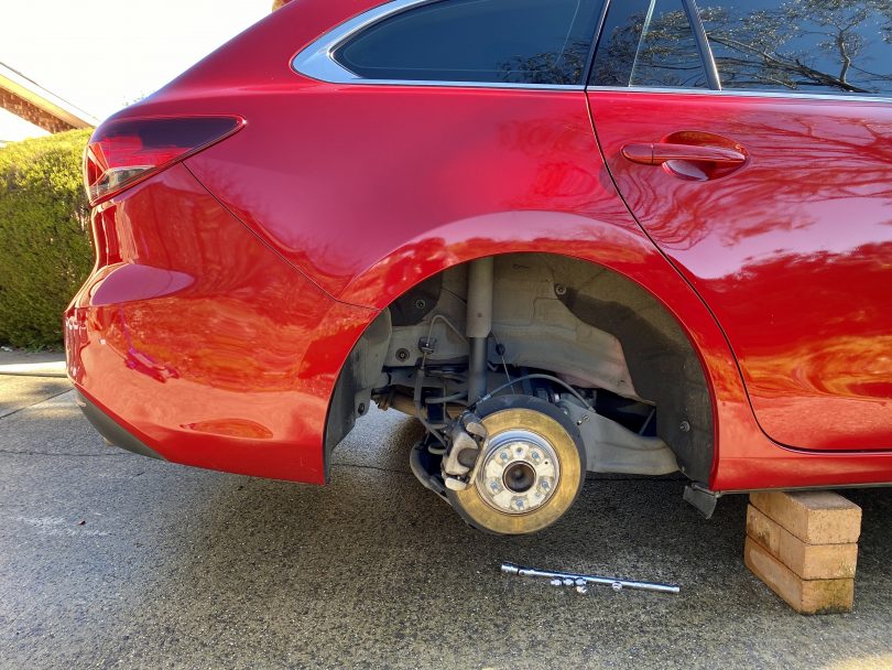 Car hoisted on bricks with wheel missing