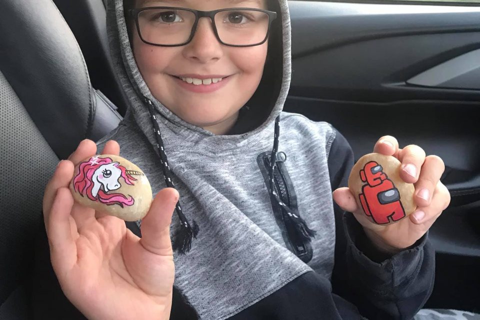 Young boy holding up painted rocks