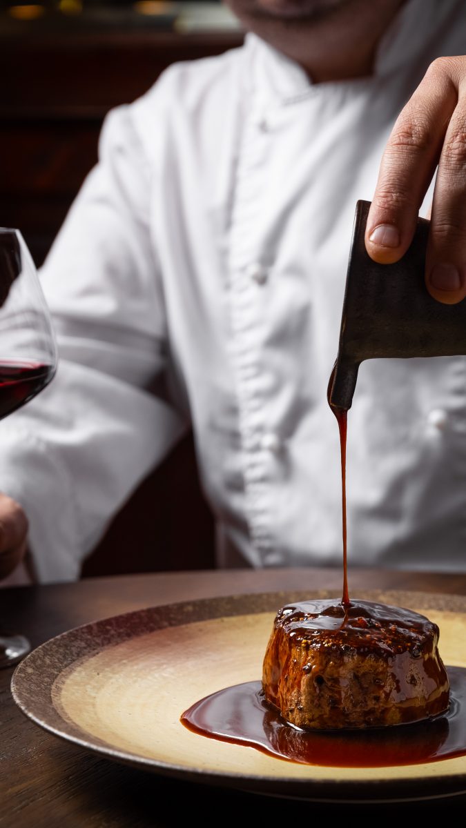 Damian pouring sauce on a steak