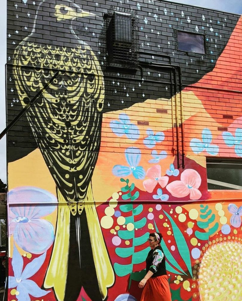 Bright mural of bird with woman walking