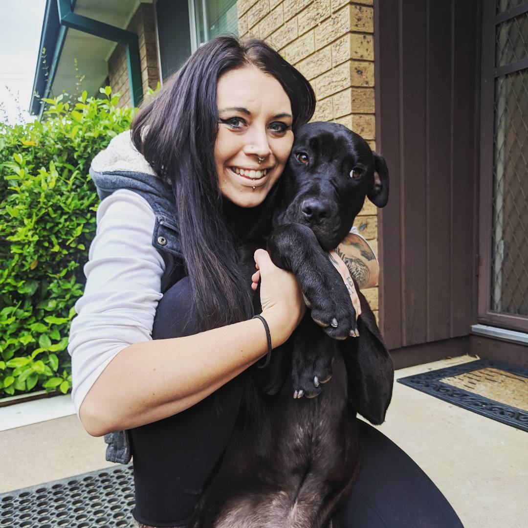 woman cuddling black dog