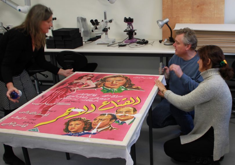 Ian Batterham and University of Canberra students working to conserve film poster