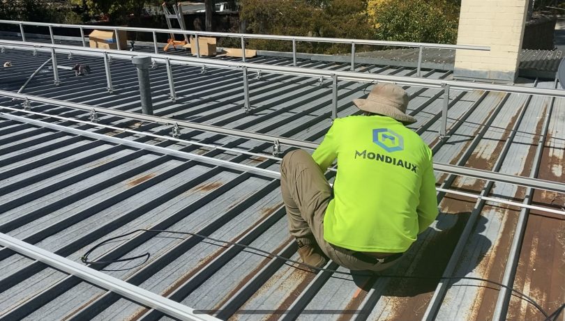 Mondiaux Solar worker installing solar panels on roof