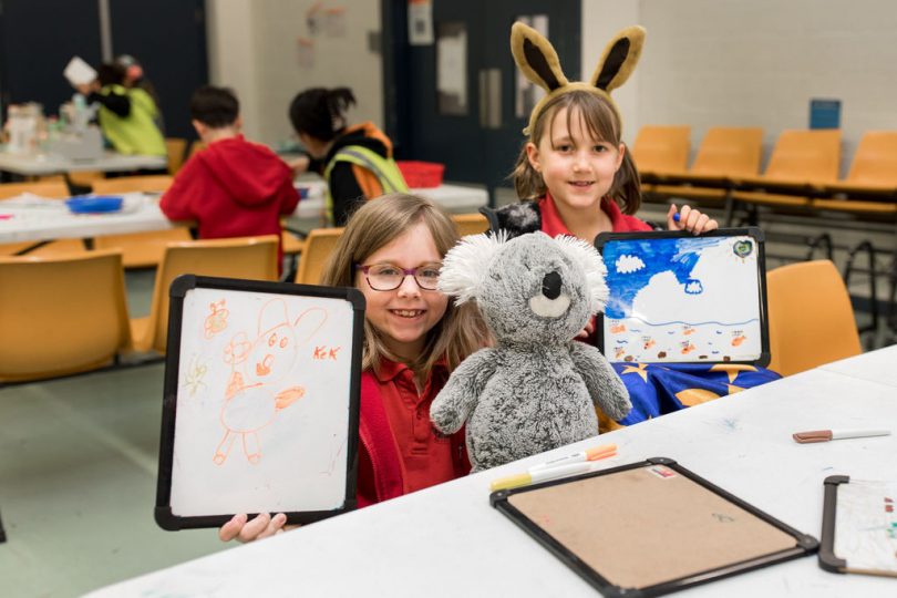 Children smiling and drawing in class