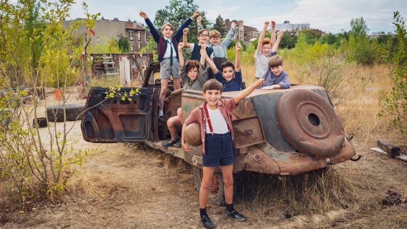 Eight young boys cheering and a rusty chassis