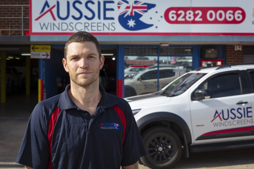 man standing in front of a car and shopfront