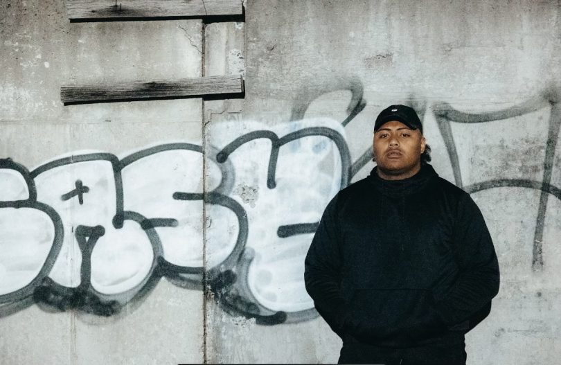 Rap artist standing in front of a graffiti wall