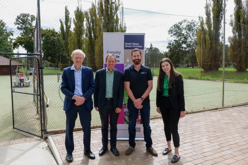 Group of people standing in front of a tennis court