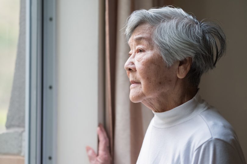 Serious senior woman looking outside window