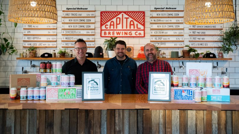 three men at bar with certificates