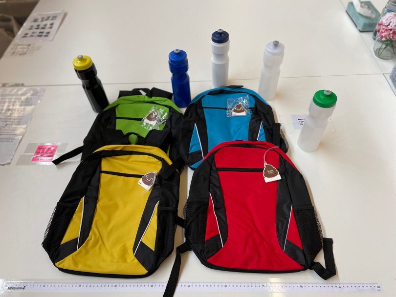 Four backpacks and five water bottle on a table