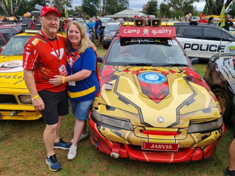 Brett Norton (Ironman), his wife (Supergirl), and 'Jarvis' the Holden on an esCarpade with Camp Quality