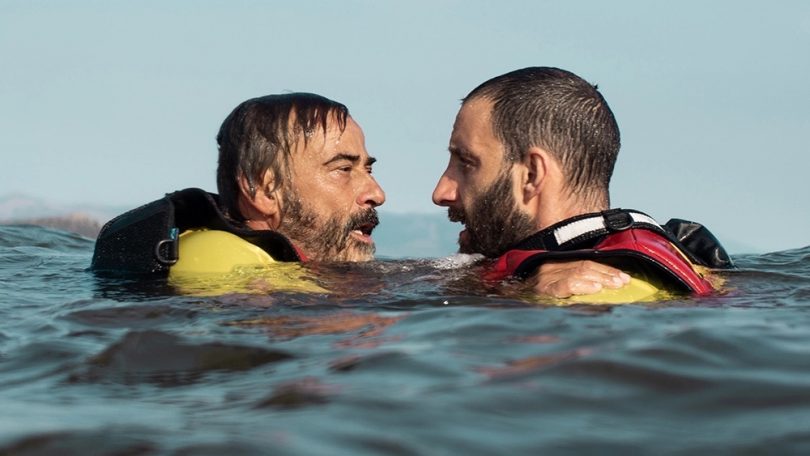 Movie still depicting two men in water