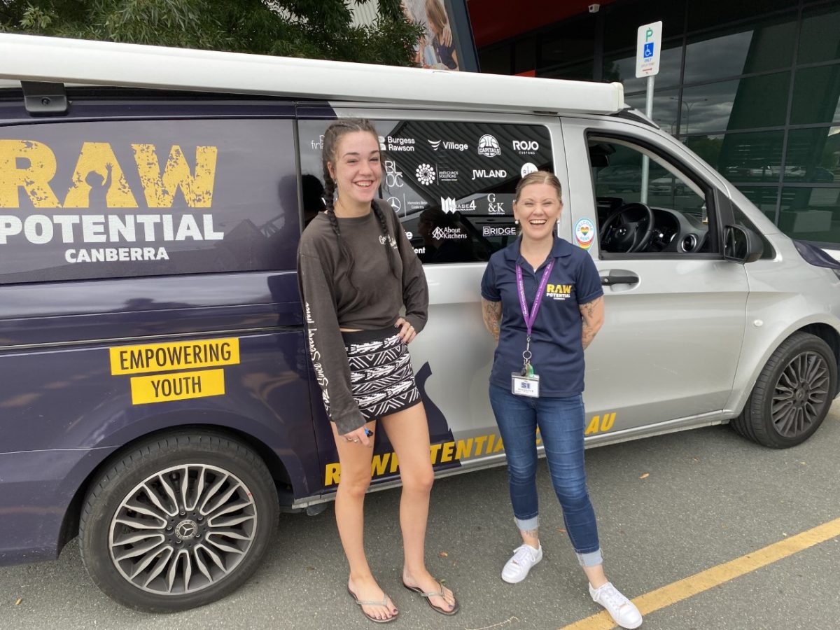 two people standing in front of Raw Potential truck