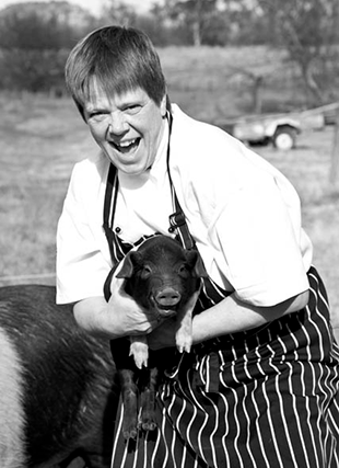 Black and white photo of woman with a piglet