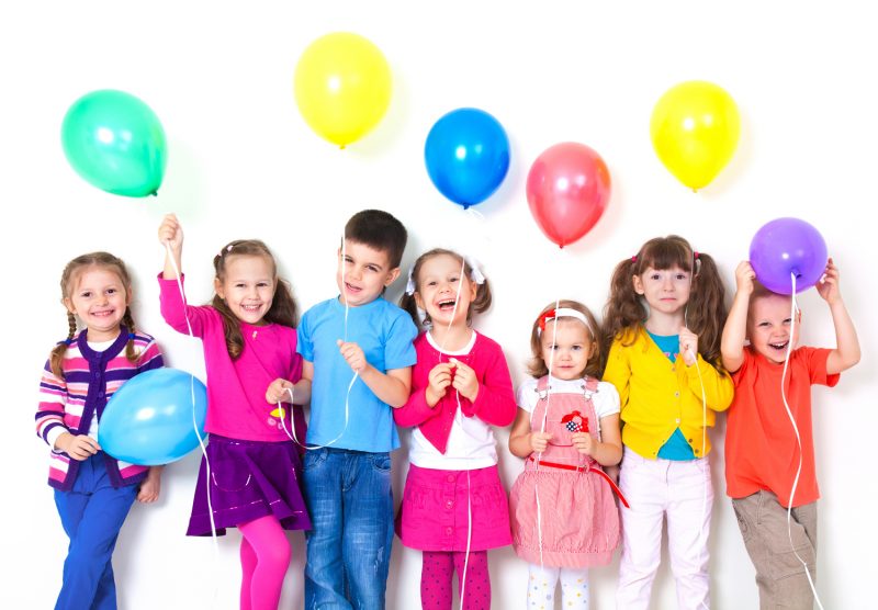 kids wearing colourful clothes holding balloons