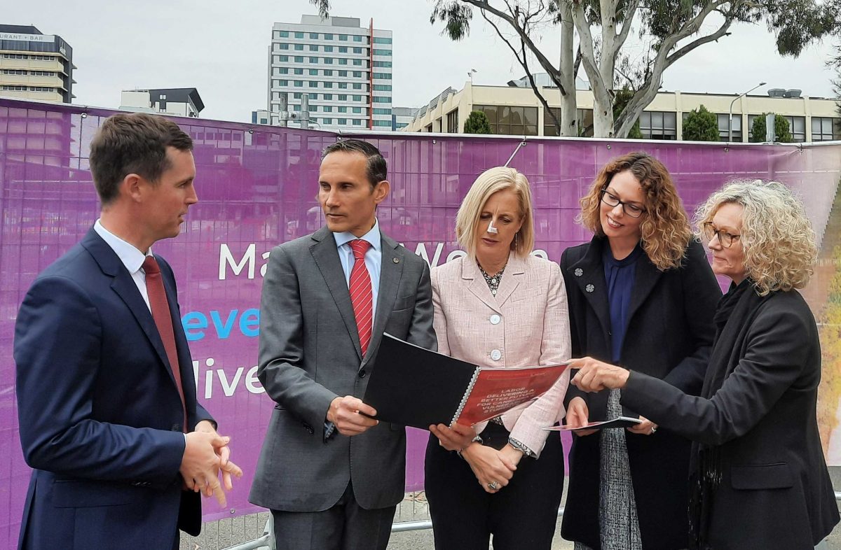 Five representatives supporting the CIT project view a plan on-site at Woden.